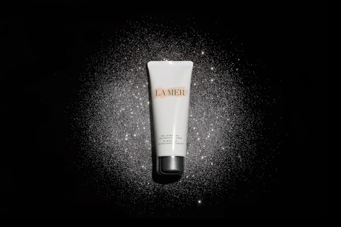 La Mer revitalizing mask tube on black glitter background. Beauty product shot with luxurious feel, studio lit, product focus.