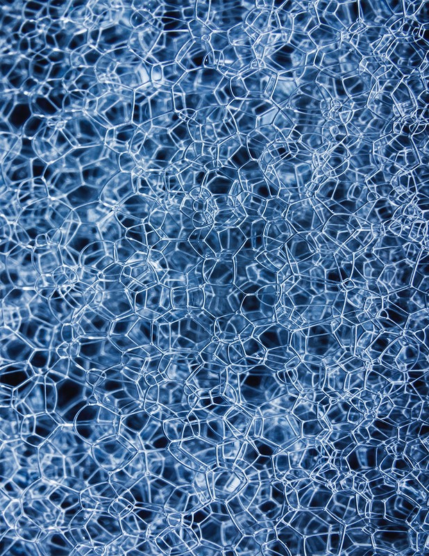 Close-up abstract image of a blue, geometric foam material with repeating hexagonal and pentagonal shapes, creating a cellular texture.