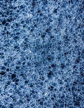 Close-up abstract image of a blue, geometric foam material with repeating hexagonal and pentagonal shapes, creating a cellular texture.