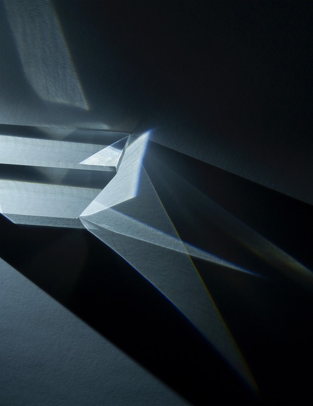 Abstract composition features geometric prisms and light interplay, creating shadows and refractions in a monochromatic color scheme.