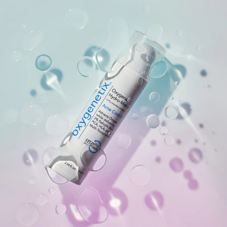 Cosmetic product, Oxygenetix Hydro-Matrix Acne Control, against a softly gradient blue and pink backdrop with water droplets.
