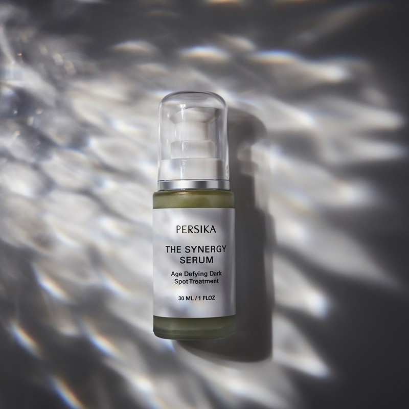 Cosmetic bottle of serum illuminated with dramatic lighting for skincare and beauty brand promotion, featuring Persika Synergy Serum.