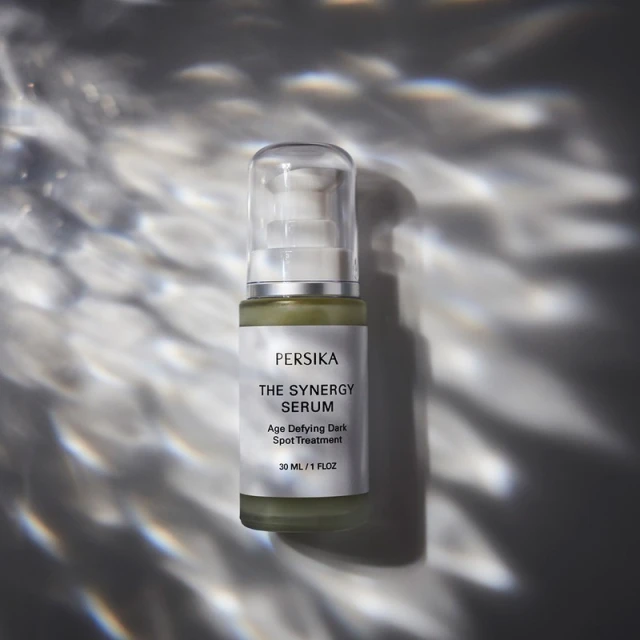 Cosmetic bottle of serum illuminated with dramatic lighting for skincare and beauty brand promotion, featuring Persika Synergy Serum.