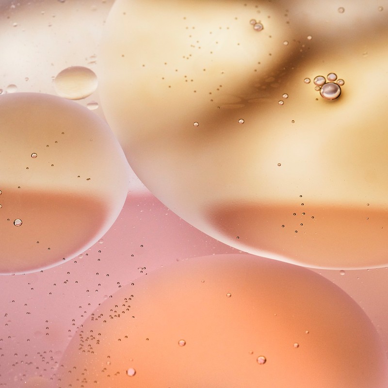 Abstract view of liquid spheres in peach, pink, and champagne tones, reflecting light and creating a calming, modern visual.