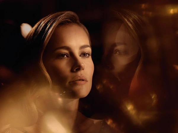 Close-up portrait of a woman with warm golden lighting and a soft reflective overlay by Sesse Lind