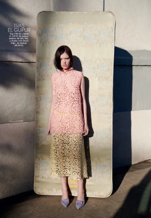 Model wearing a pink lace top and yellow lace skirt standing in front of an upright floral mattress.
