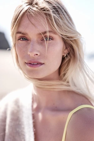 Close-up portrait of a woman with blonde hair and natural makeup outdoors