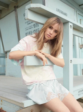 Adult female posing outdoors in front of lifeguard tower wearing a pastel tie-dye t-shirt and pale blue lace-trimmed shorts.