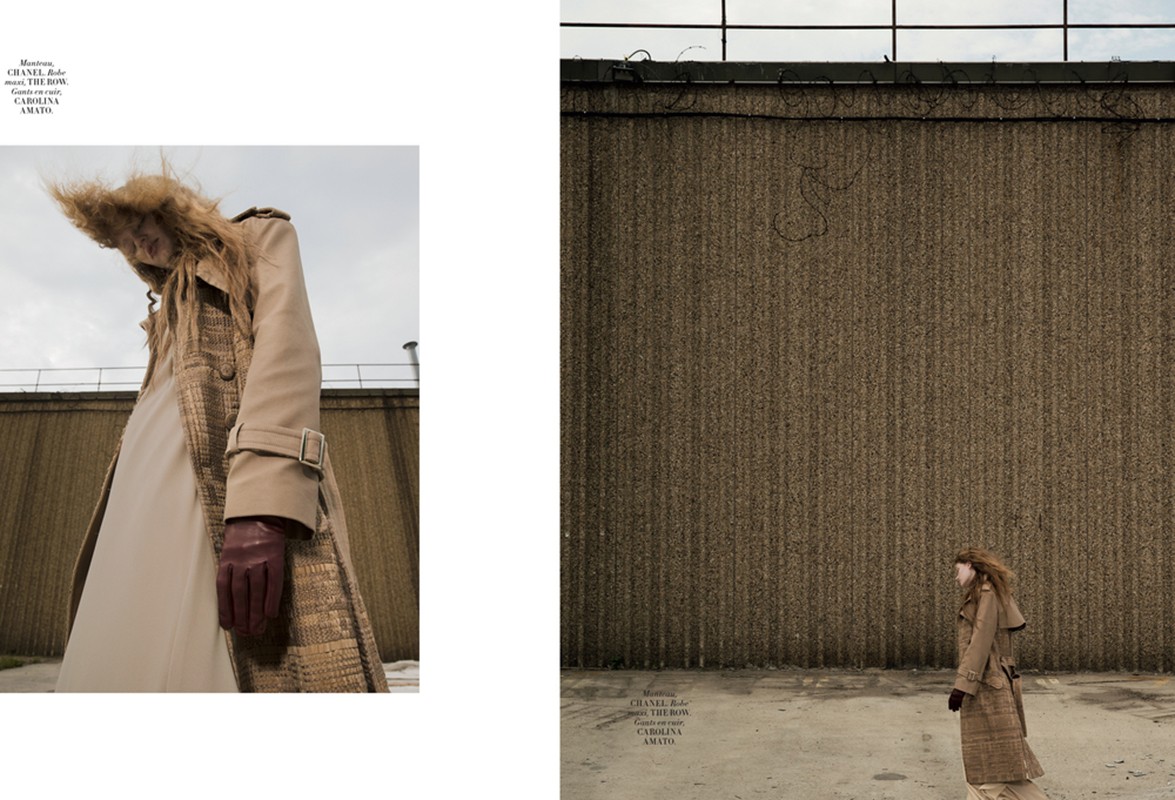 A fashion shot featuring a long-haired female model in a trench coat, paired with leather gloves. She is set against a textured wall.
