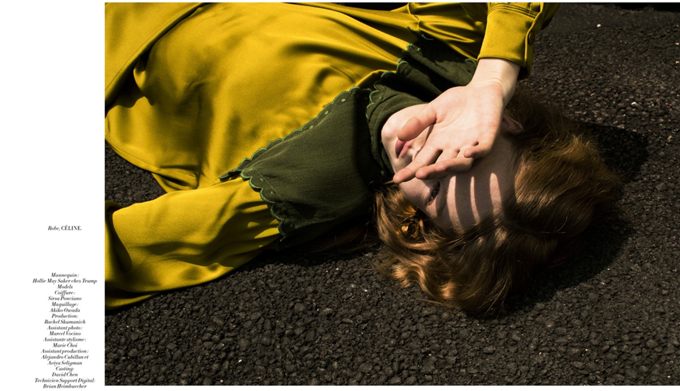 Woman in yellow dress lying on pavement covering face with hand. Fashion editorial photography featuring outdoor natural lighting.