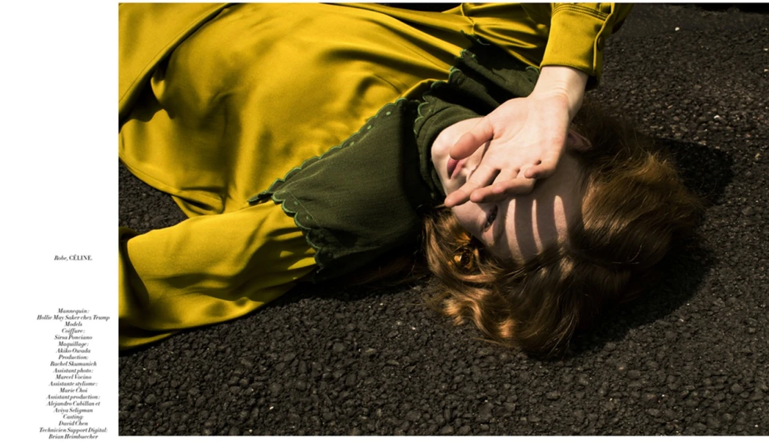 Woman in yellow dress lying on pavement covering face with hand. Fashion editorial photography featuring outdoor natural lighting.
