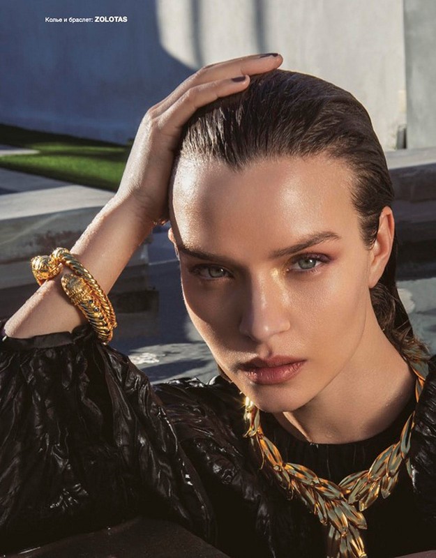 Close-up of a woman with wet hair and dramatic eye makeup wearing a gold necklace and bracelet by ZOLOTAS in a beauty editorial.