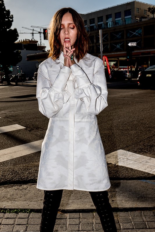 Woman in a white button-up dress and black boots posing on a city street styled by Soaree Cohen in Los Angeles.