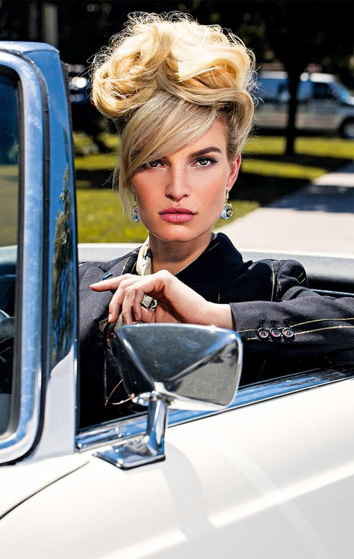 Model with voluminous blonde updo hairstyle sitting in a white convertible car