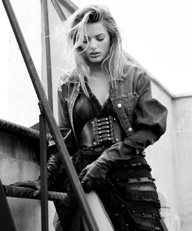 Monochrome fashion portrait of a woman wearing a denim jacket and leather gloves while descending metal stairs.