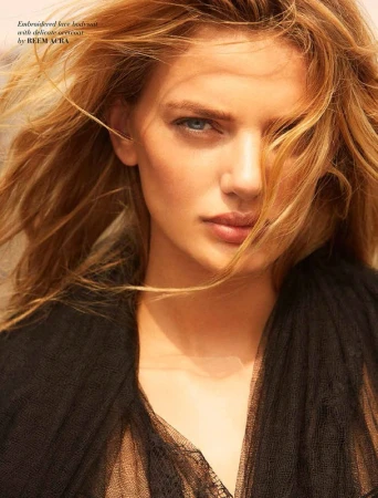 Close-up portrait of a woman with blowing blonde hair wearing a black lace top with make-up by Stefanie Willmann.