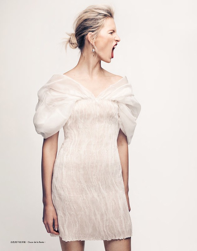 Blonde adult female with open mouth and organza dress in a studio portrait with white background. Fashion editorial photography.