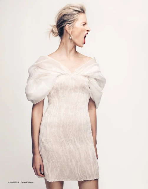 Blonde adult female with open mouth and organza dress in a studio portrait with white background. Fashion editorial photography.