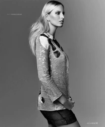 Monochrome portrait of a female model in profile wearing a sequined jacket with dark shorts against a grey studio backdrop.