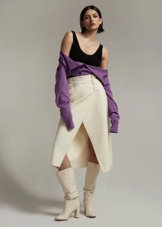 Model in a black tank top, cream wrap skirt, and purple cardigan styled by Steph Ashmore against a grey studio background