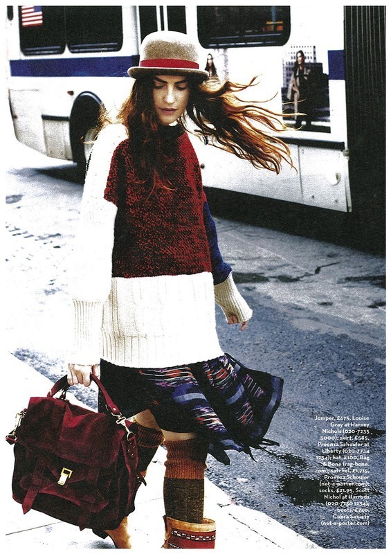 Woman in color-block sweater and bowler hat walking past a bus in Los Angeles, styled by Stephanie Peterson.