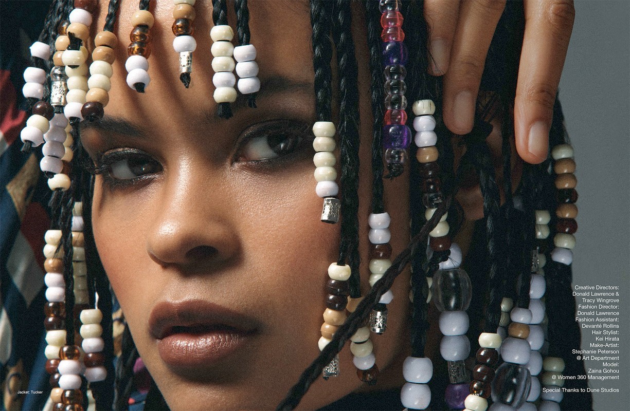 Close-up of a young adult female with dark braided hair adorned with colorful beads, showcasing a fashion-forward hairstyle and beauty look.