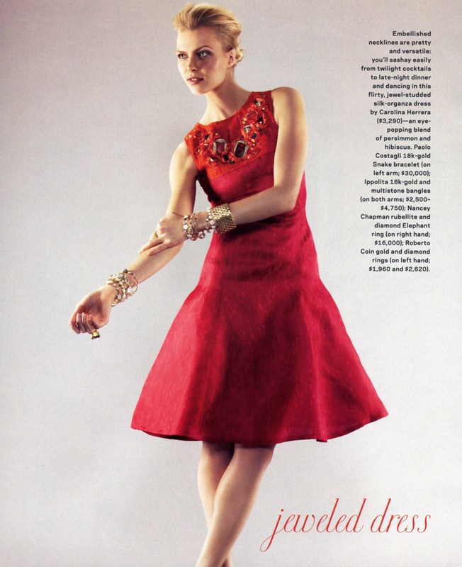 Fashion editorial shot of a female model in a red sleeveless dress with jeweled neckline, gold bracelets, and updo hairstyle on a neutral background.