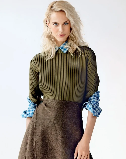 Fashionable woman in olive green top and brown skirt poses in a studio. Portrait of a female model in stylish clothing.