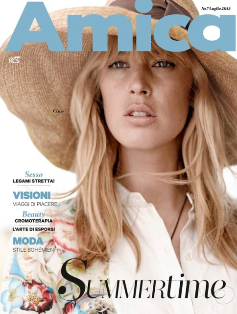 Magazine cover featuring a fair-skinned woman with blonde hair and a wide-brimmed hat, showcasing fashion and beauty elements.