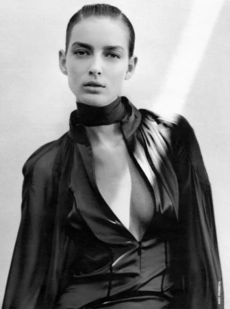 Monochrome portrait of a model with sleek hair and dark top against a light wall background