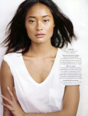 Portrait of a woman with long dark hair wearing a white v-neck t-shirt against a plain white background with printed interview text