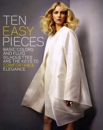 Model with voluminous blonde hair wearing a cream colored draped coat against a grey studio background with overlaid text.