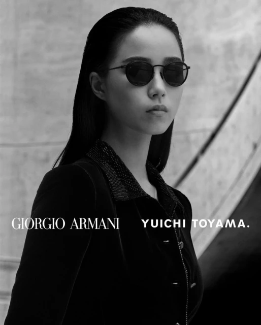 Black-and-white portrait of an Asian woman wearing sunglasses and a dark jacket, with the Giorgio Armani logo visible in the foreground.
