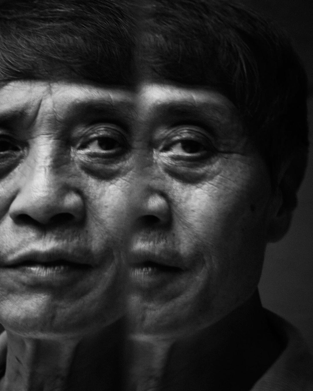 Monochrome portrait of an older adult with short hair, featuring a double exposure effect enhancing facial details and textures.