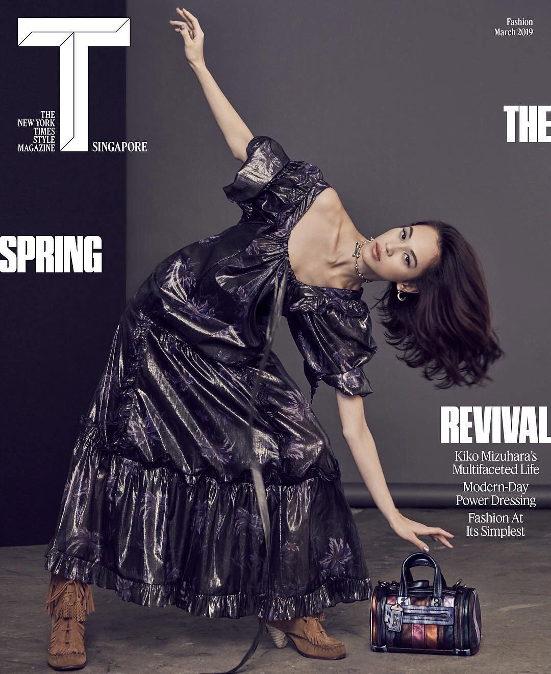 Fashion editorial magazine cover featuring a model in a metallic dress and ankle boots next to a patterned satchel, shot in a studio.