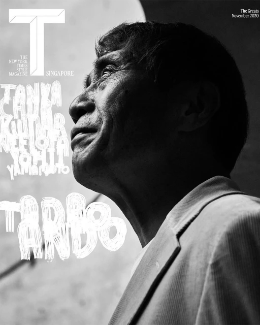Black and white magazine cover featuring a close-up of an elderly Asian man in a light-colored suit, looking upwards with soft lighting.