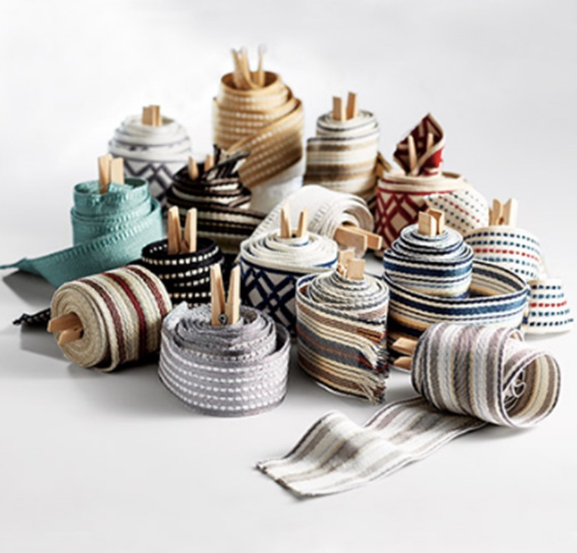 Collection of rolls of patterned and textured ribbon, held in place by small wooden clips. Ribbons are on a white surface.