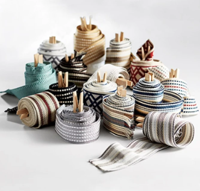 Collection of rolls of patterned and textured ribbon, held in place by small wooden clips. Ribbons are on a white surface.