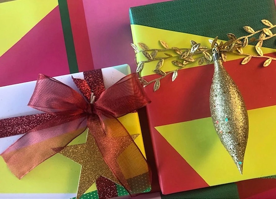 Two colorful Christmas presents, one with a large gold star and red bow, another with a decorative gold vine and teardrop ornament.