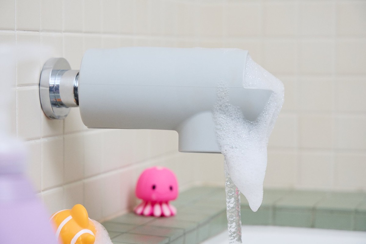 A close-up showcases a faucet with a foam spout and water running, complemented by two children's bath toys.