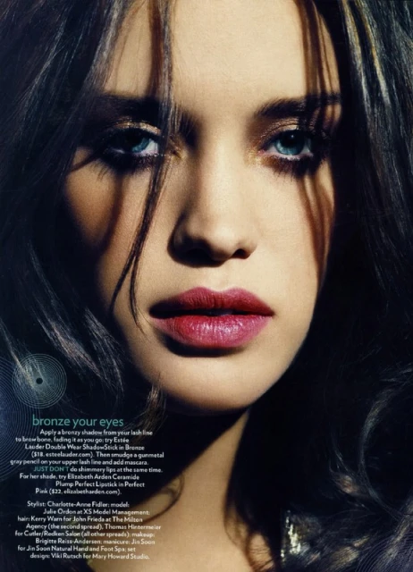 Close-up portrait of a brunette woman with red lipstick and blue eyes, showcasing beauty and cosmetic aesthetics.