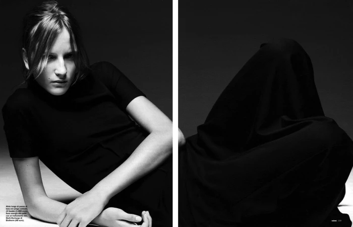 Monochrome studio shot: A woman in black attire and a draped form create a study in shadows and light, emphasizing texture and form.