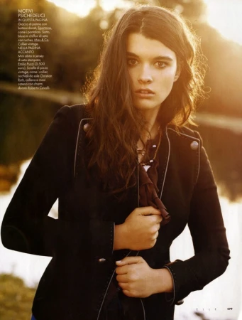 A dark-haired woman in a black jacket outdoors with warm backlight by hair stylist Thomas Hintermeier.