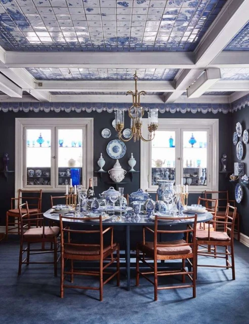 Formal dining room showcasing an oval table set for a meal, surrounded by wooden chairs and blue and white ceramic decor.