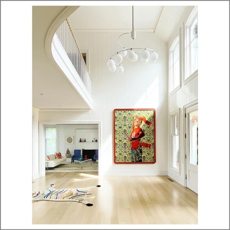 Bright, high-ceilinged interior with a large painting of a person in red tones, modern chandelier, and a view into a living area.