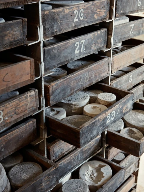 A collection of wooden drawers filled with round, textured stones, each drawer labeled with a unique number in an indoor environment.