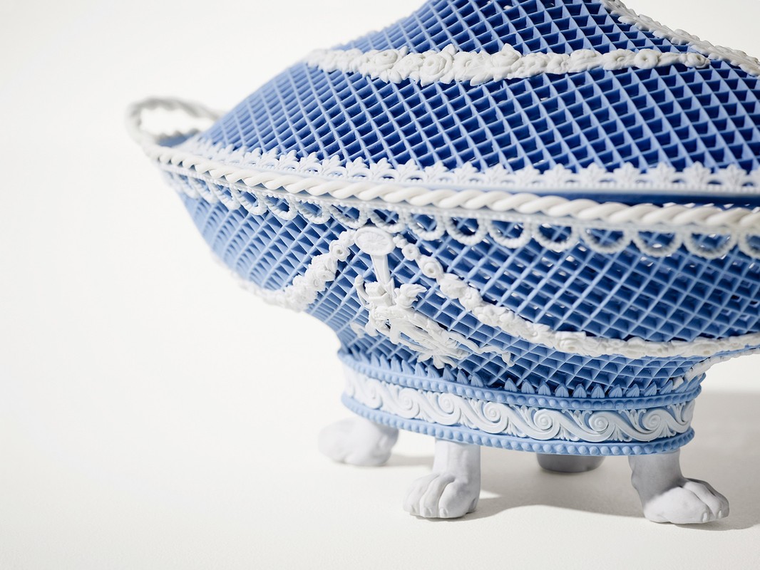 Intricate blue and white decorative object with lattice design and ornate details, on a white background. Close-up shot.