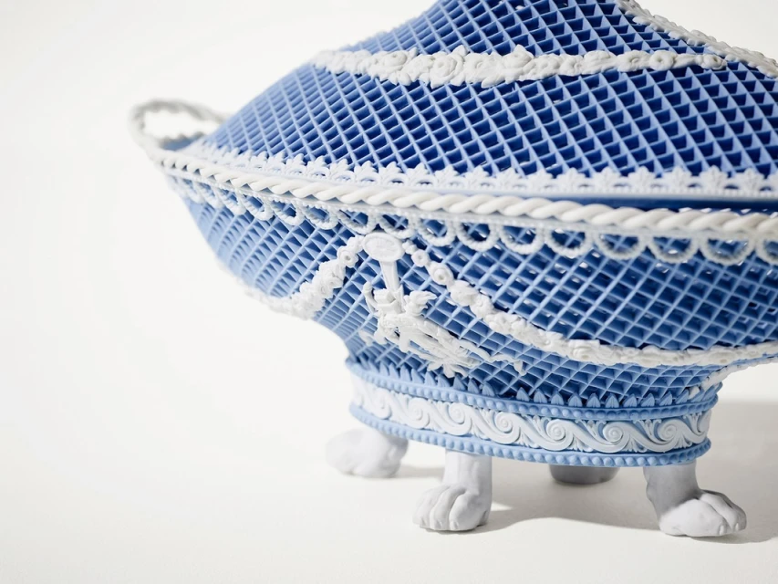 Intricate blue and white decorative object with lattice design and ornate details, on a white background. Close-up shot.