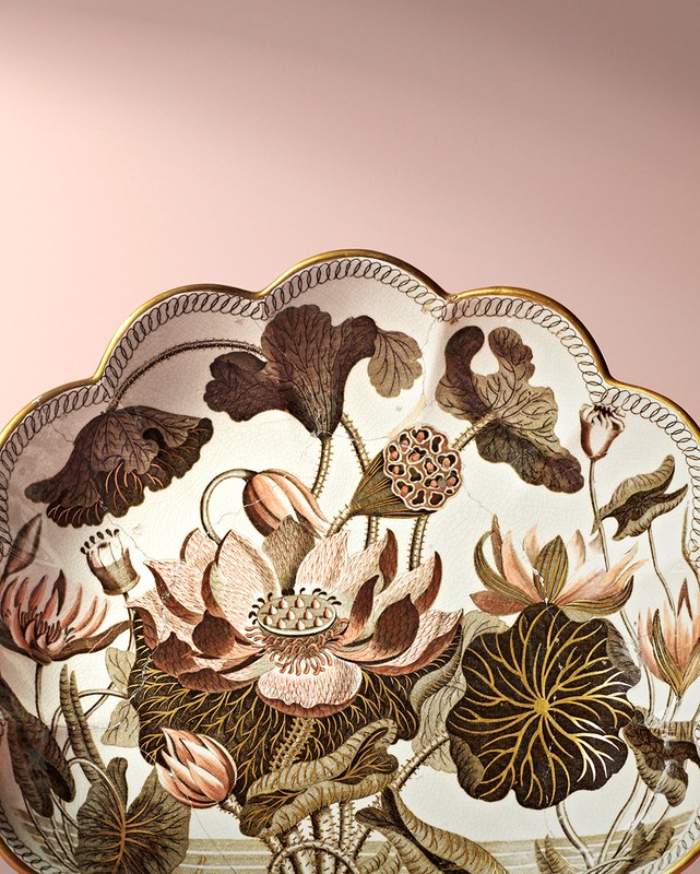 Decorative plate with a botanical illustration of lotus flowers, rendered in brown and pink hues against a pale pink backdrop.