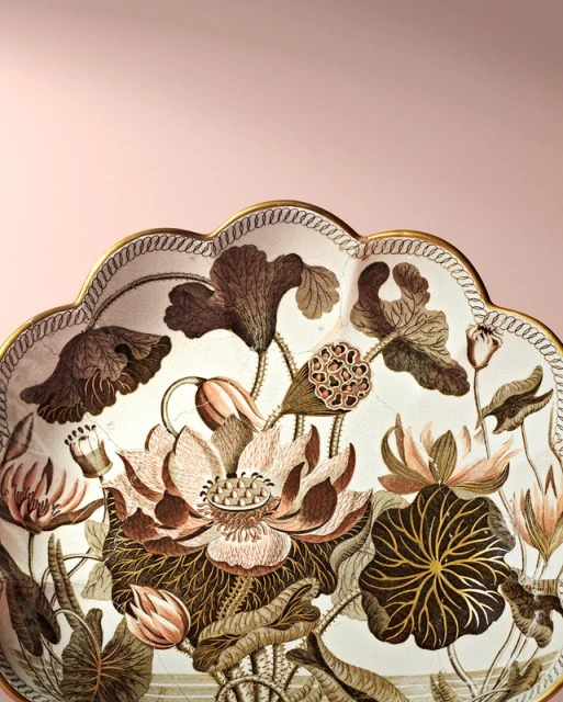 Decorative plate with a botanical illustration of lotus flowers, rendered in brown and pink hues against a pale pink backdrop.